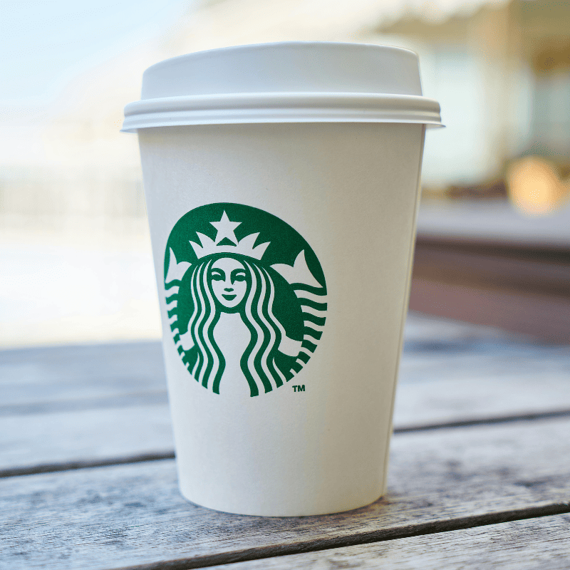 um copo branco da starbucks em cima de uma mesa